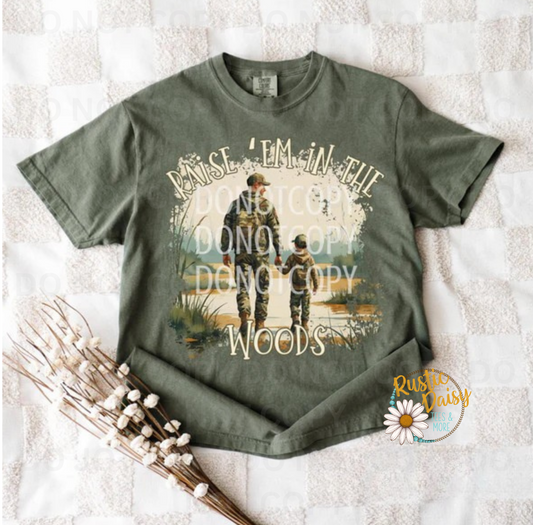 T-shirt with RAISE 'EM IN THE WOODS text with silhouette of adult and child walking in outdoor landscape with trees and sunset