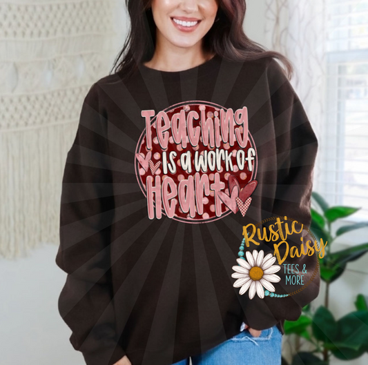 T-shirt with TEACHING IS A WORK OF HEART text in pink letters on red circle with hearts and polka dots